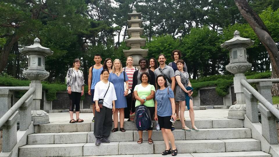a group of people are posing for a picture in front of a stone lantern