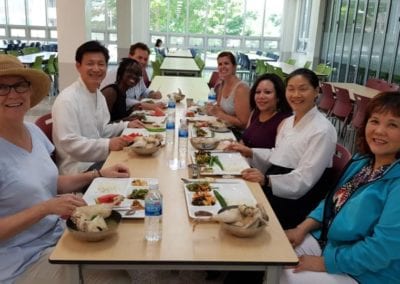 Eight people sitting at a long lunch table looking at the camera