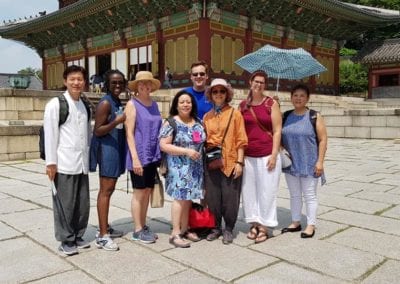 Group of people standing in front of a Korean Pagoda.