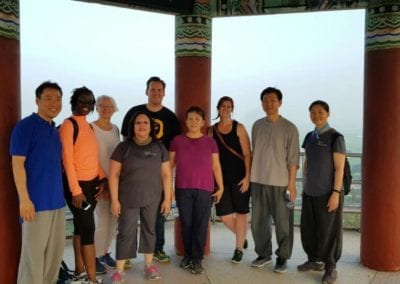 Group of people standing under a Korean pavilion with foggy background