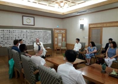 Man in traditional clothing leading a discussion with group of people surrounding him