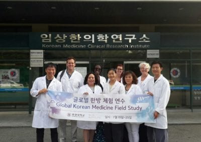 Doctors in front of Korean Medicine Clinical Research Institute holding "Global Korean Medicine Field Study" sign