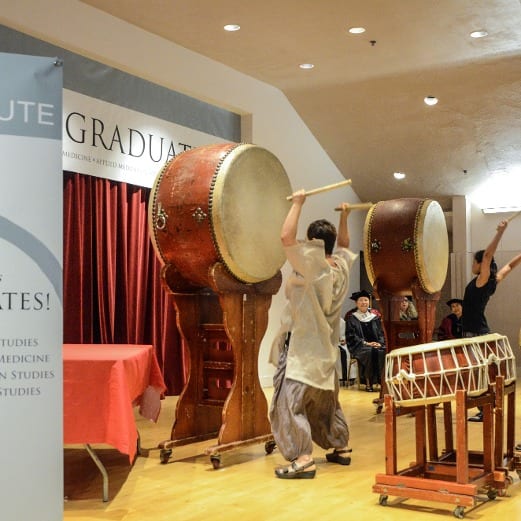 people playing drums in front of a sign that says graduate