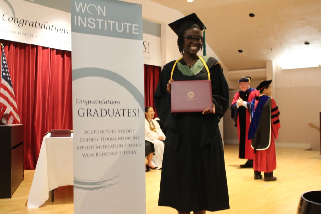 a woman stands in front of a sign that says congratulations graduates