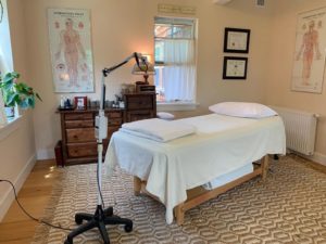 a room with a massage table and a poster on the wall that says acupuncture chart