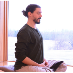 a man sits in a lotus position with his eyes closed