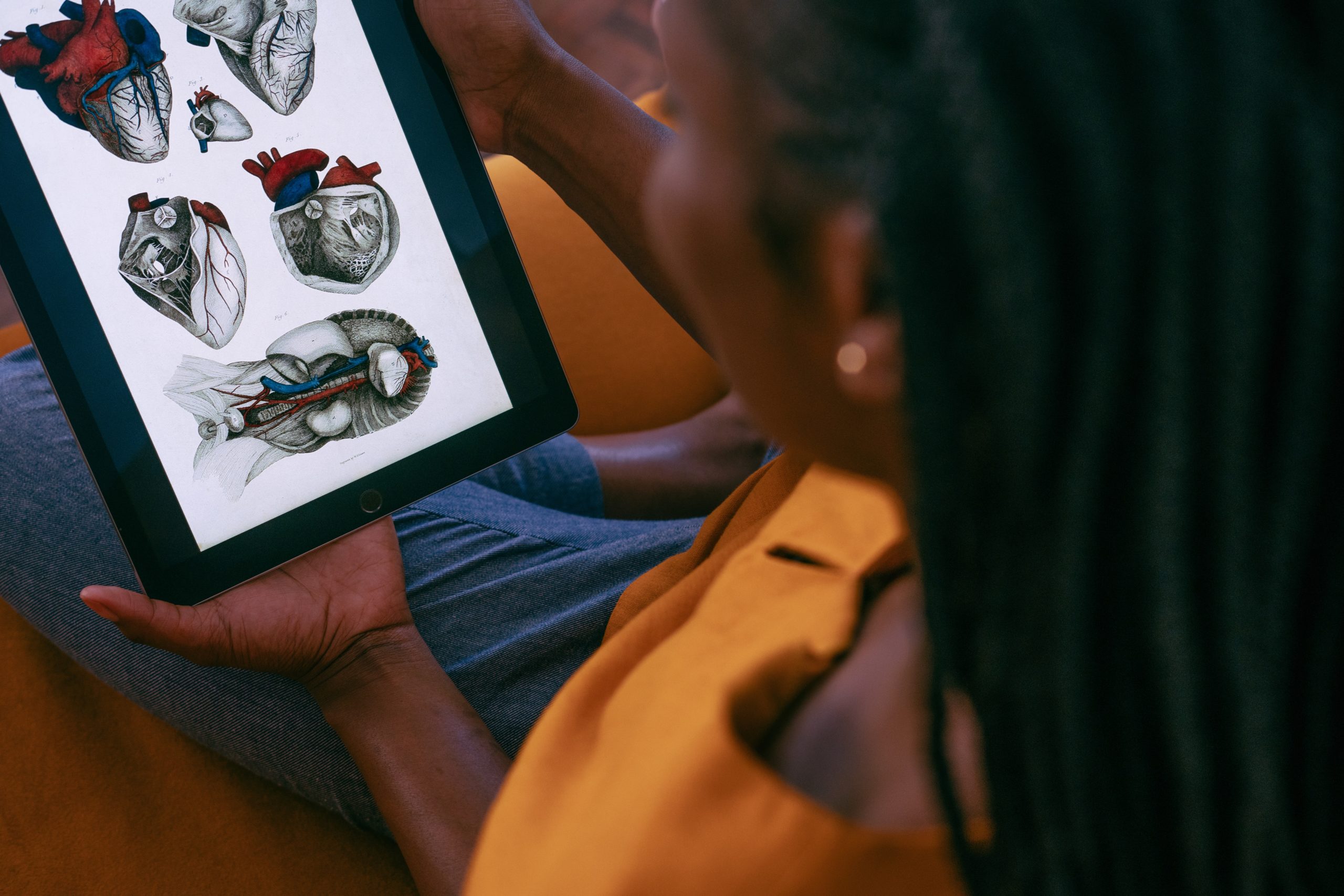 a woman is holding a tablet with drawings of anatomical hearts on it