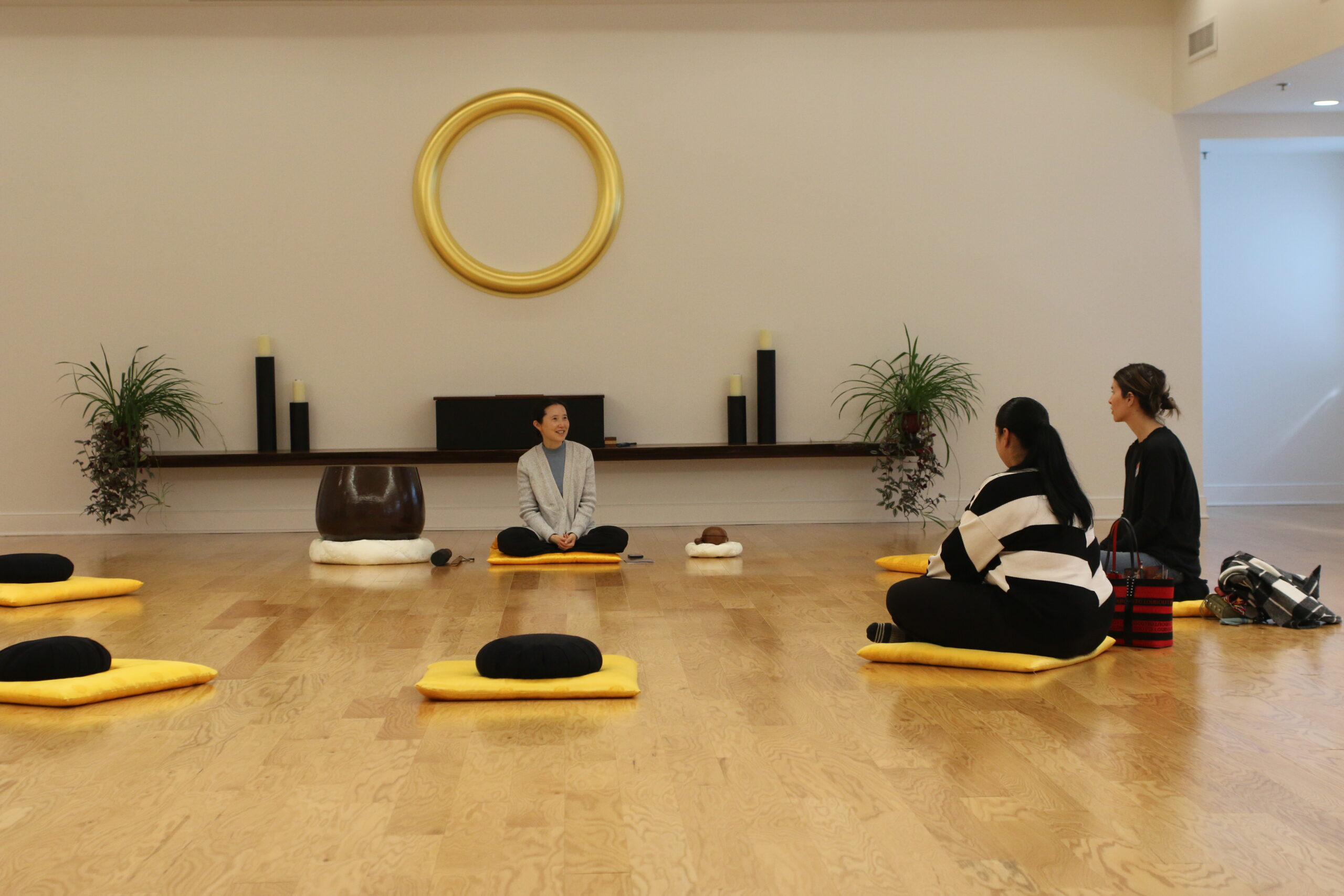 A group of people sitting on yellow mats in a room meditating 